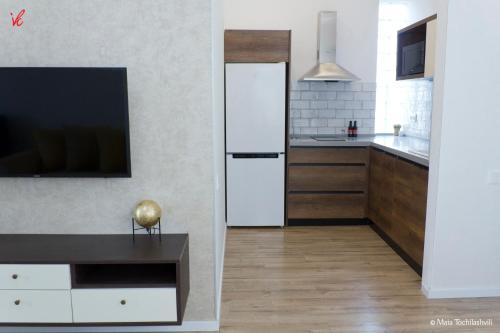 Il comprend une cuisine équipée d'un réfrigérateur blanc et une télévision. dans l'établissement Sameba Bell, Luxury Apartment, à Tbilissi