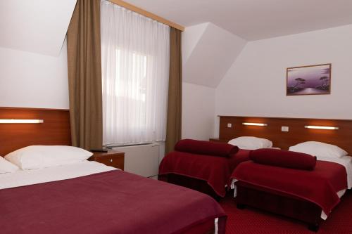 um quarto de hotel com duas camas com lençóis vermelhos em Hotel Mirni Kutak em Otočac