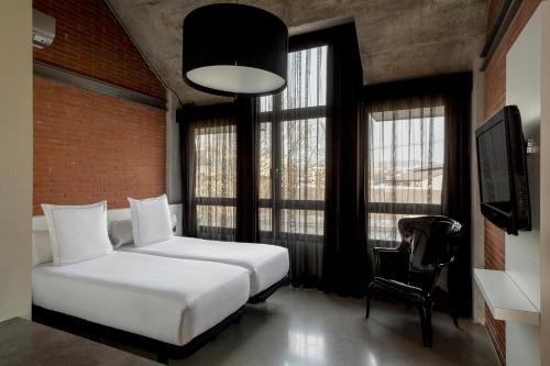 a bedroom with a bed and a chair and windows at Barcelona Apartment Republica in Barcelona