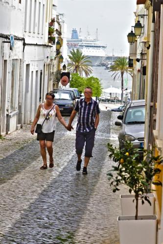 a man and woman walking down a street holding hands at Rocha Prestige - Guest House and Suites in Portimão