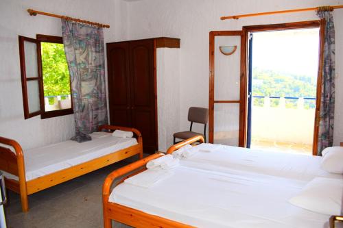 a room with two beds and a large window at Rizos Veranda - Rooms in Isómata