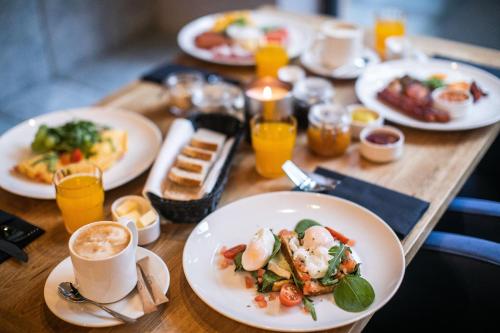 a wooden table topped with plates of food and drinks at Hotel Vesper House in Gdańsk