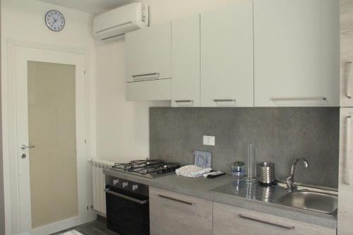 a kitchen with white cabinets and a sink and a stove at Agriturismo La Fraterna in Tolle