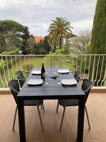 - une table noire avec des chaises et une bouteille de vin dans l'établissement Les Palmiers, à Saint-Cyr-sur-Mer