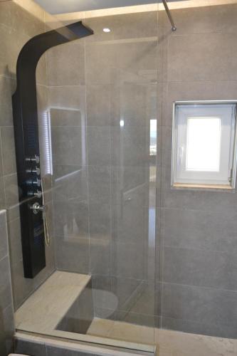a glass shower in a bathroom with a window at ''Stergiou Luxury Apartments'' με κοινη πισινα in Saronida