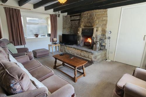 a living room with a fireplace and a couch and a table at Cornerstones Cottage, Tideswell in Tideswell