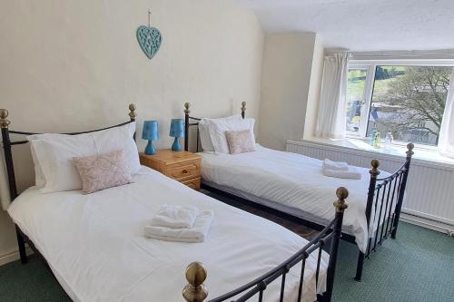 two twin beds in a room with a window at Cornerstones Cottage, Tideswell in Tideswell