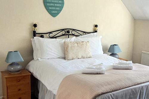 a bedroom with a bed with white sheets and two lamps at Cornerstones Cottage, Tideswell in Tideswell