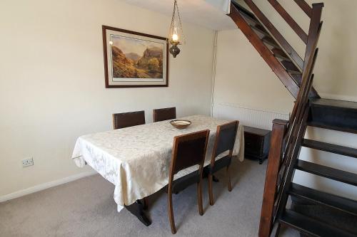 a dining room with a table with chairs and a staircase at Cornerstones Cottage, Tideswell in Tideswell
