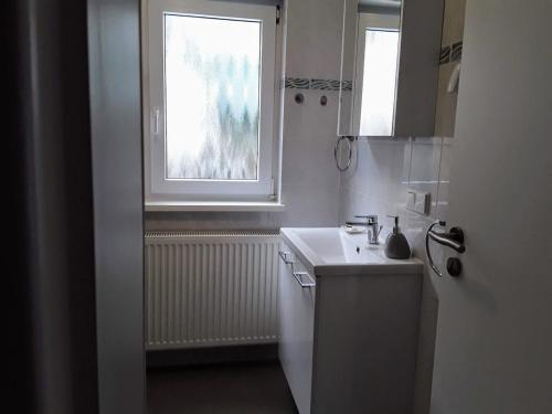 une cuisine blanche avec un évier et une fenêtre dans l'établissement Ferienwohnung Hans, à Lindenfels