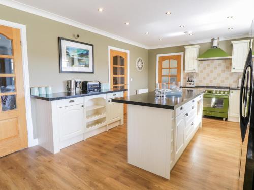 a large kitchen with white cabinets and black counter tops at Ger Y Mor in Cemaes Bay
