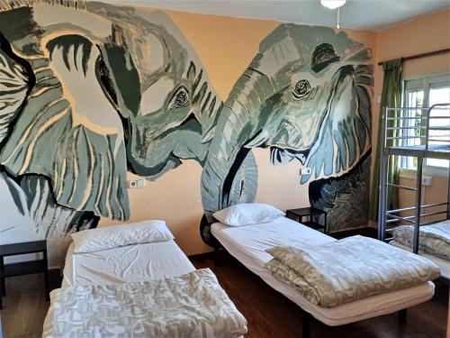 a room with two beds and a mural on the wall at La Casa Verde in Murcia