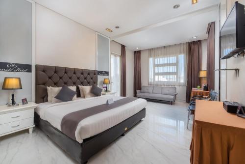 a large bedroom with a large bed and a desk at Life Emerald Hotel Surabaya in Surabaya