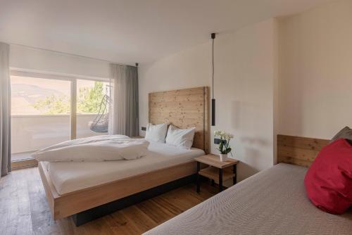 a bedroom with two beds and a large window at Wanderhotel Teiserhof in Funes