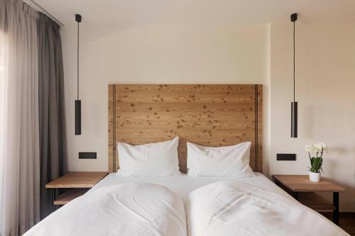 a bedroom with a white bed with two pillows at Wanderhotel Teiserhof in Funes