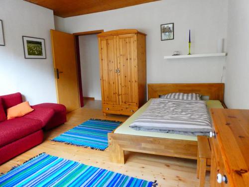 - une chambre avec un lit et un canapé rouge dans l'établissement Ferienwohnung Maidenhain, 