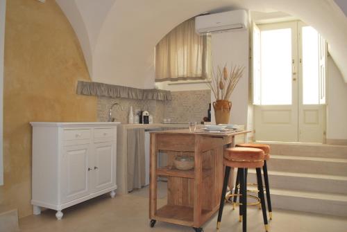 uma cozinha com uma mesa e um balcão com um banco em Casetta Melograno em Fasano