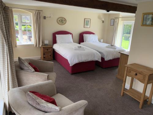 2 camas en una habitación con sofá y silla en The Coppleridge Inn en Motcombe