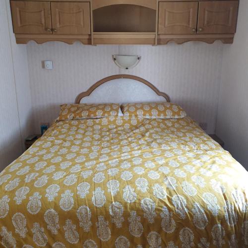 a bed with a yellow and white comforter in a room at Home from home private host in Skegness