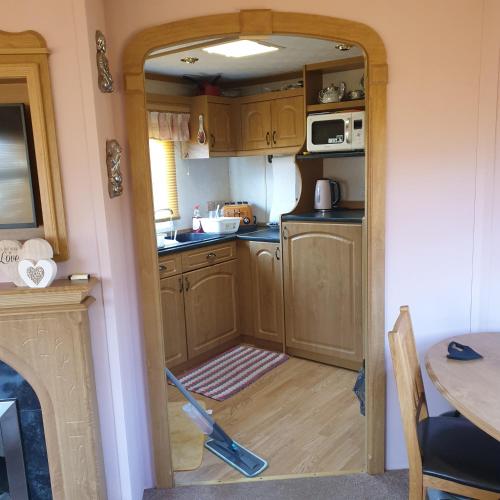 una cucina con armadi in legno e una porta aperta di Home from home private host a Skegness