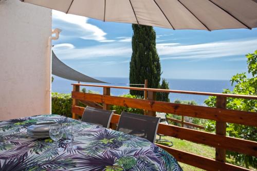 a table and chairs with an umbrella on a balcony at vita nova in Santa-Maria-di-Lota