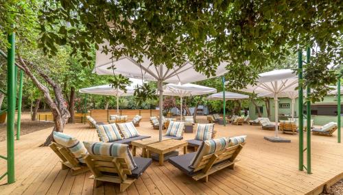 達夫納的住宿－Camping Dafna - By Travel Hotel Chain，一个带桌椅和白色遮阳伞的庭院。