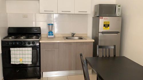 a small kitchen with a stove and a sink at Like Home Apartment !!! 2 bedrooms full apartment in La Ureña