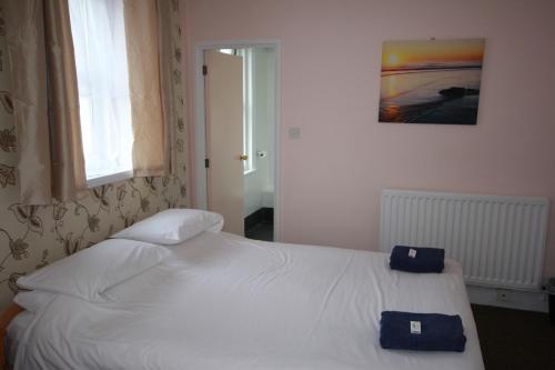 a bedroom with a white bed with two blue towels on it at Dolphins Hotel in Bournemouth