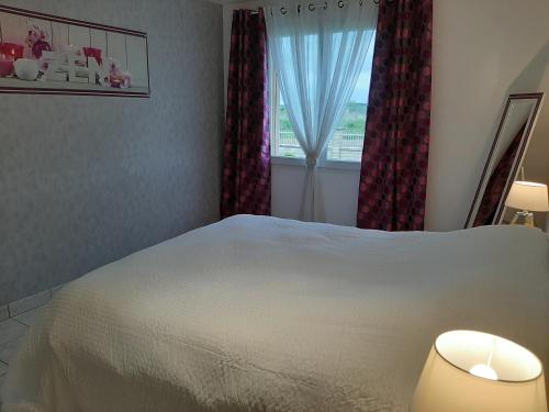 a bedroom with a white bed and a window at Les lits de la Py in Sommepy-Tahure