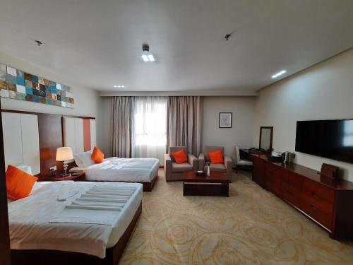a hotel room with two beds and a flat screen tv at Karam Al Diyafa Hotel in Jeddah