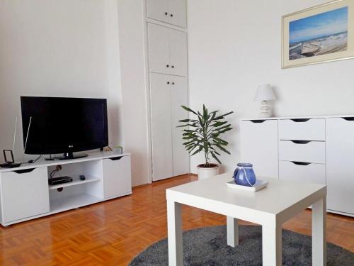 een witte woonkamer met een tv en een tafel bij Apartmani Katica in Diklo