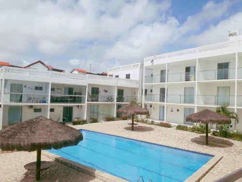 um hotel com piscina e guarda-sóis em apartamento em jacumã- residencial granito x jasmim em Jacumã