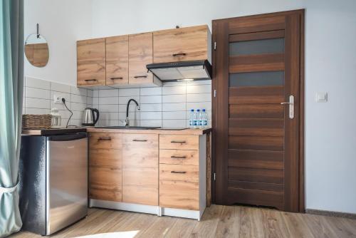 a kitchen with wooden cabinets and a stainless steel refrigerator at Willa Zator in Oświęcim
