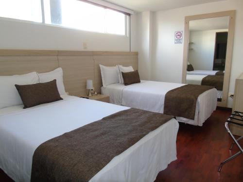 a hotel room with two beds and a mirror at Hotel Paradise del Cafe in Pereira