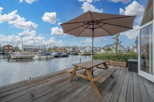 a wooden picnic table with an umbrella on a dock at Meerzicht 70 - Vakantiehuis aan het water! in Uitgeest