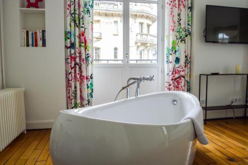 una vasca da bagno bianca in una stanza con finestra di Les Berceaux de la Cathedrale a Reims