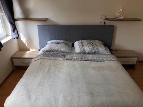 Bett mit grauem Kopfteil in einem Schlafzimmer in der Unterkunft Ferienwohnung Stiftsgartenblick in Sankt Lambrecht