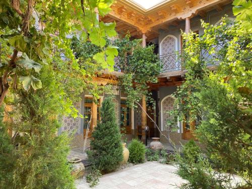 a house with a porch with trees and plants at Grand Nodirbek Boutique Hotel in Bukhara