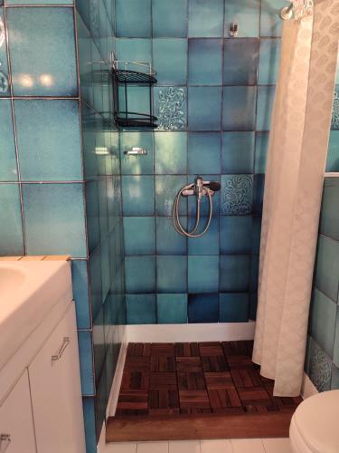 y baño con ducha de azulejos azules. en Beach House Emme, en Palaión Tsiflíkion