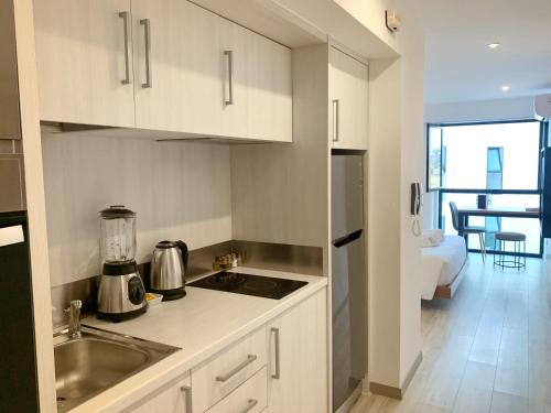 a kitchen with white cabinets and a sink and a stove at Bright 1BR in Barranco in Lima