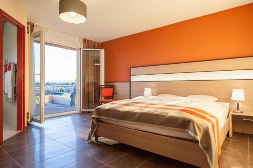 ein Schlafzimmer mit einem großen Bett und einer orangefarbenen Wand in der Unterkunft Hotel Lacotel in Avenches