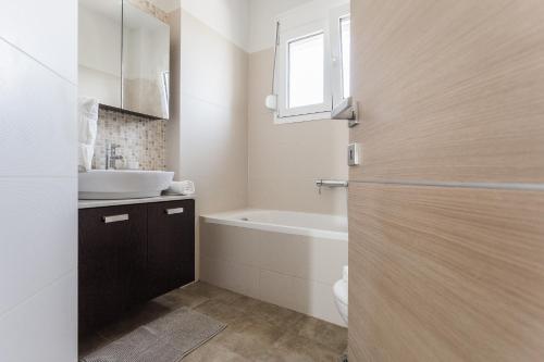 a bathroom with a sink and a tub and a toilet at Μodern apartment with big garden in Epanomi