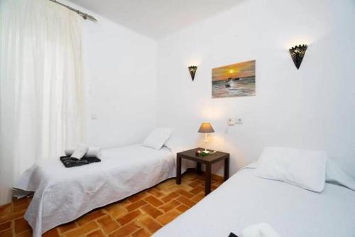 2 Betten in einem weißen Zimmer mit einem Tisch in der Unterkunft 4 persoons bungalow met gemeenschappelijk zwembad in Teulada
