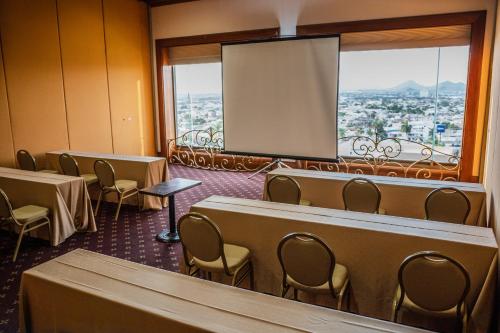 a conference room with tables and chairs and a screen at Hotel San Luis Lindavista in Culiacán