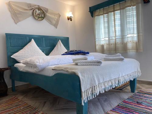 a blue bed with white pillows and a clock on the wall at Casa Soarelui in Murighiol