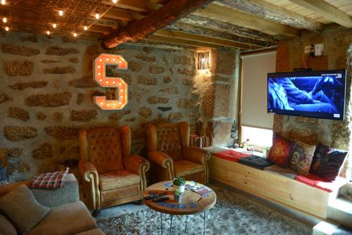 a living room with a large letter s on a stone wall at Casa dos Alcaides in Sabugueiro