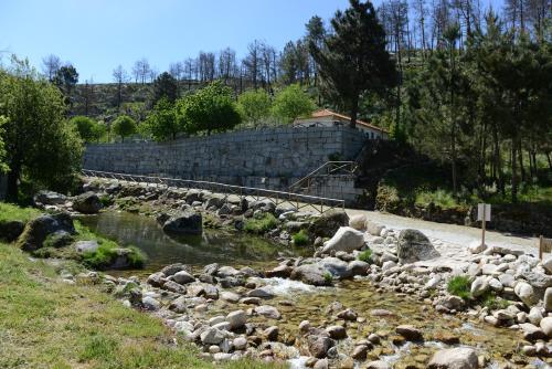 a river with rocks in front of a building at Casa dos Alcaides in Sabugueiro