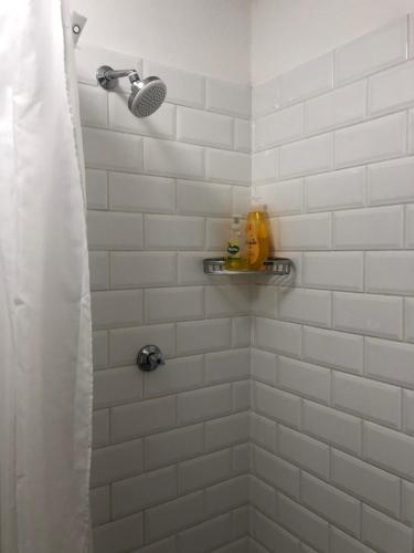 a white tiled shower with a shower head at Just a Bed in Stellenbosch