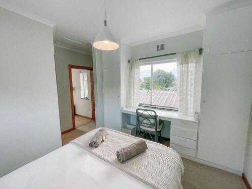 a bedroom with a bed and a desk and a window at Leisure Isle Loft Apartment in Knysna