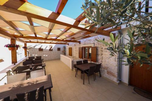 an outdoor patio with tables and chairs and wooden ceilings at Apartmani Dvor Betina in Betina